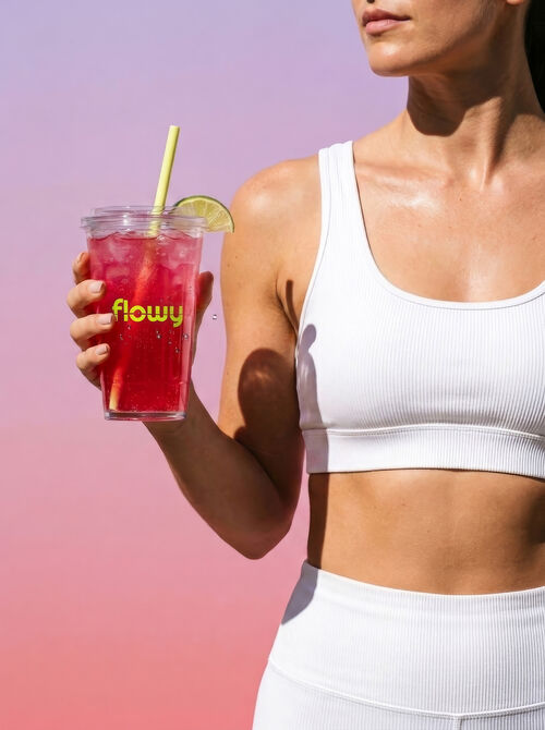 Woman in activewear holding an iced Flowy lemon lime drink